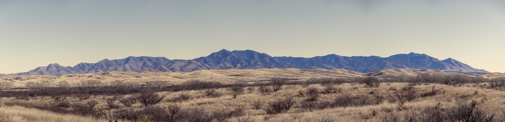 Panorama of a distant mountain range with hills covered in grass in the forground in Arizona.