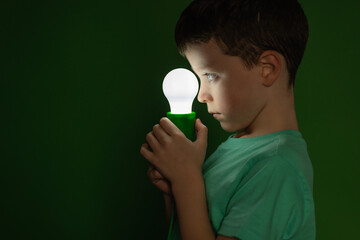 Little boy with light bulb in dark room