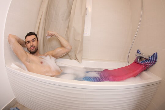 Adult man with merman costume in the bathtub 