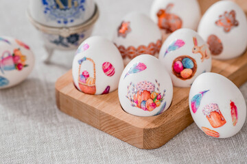 A large egg-box with the inscription XB and Easter eggs on a linen tablecloth on the table. The concept of the Bright Easter holiday.