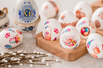 A large egg-box with the inscription XB and Easter eggs on a linen tablecloth on the table. The concept of the Bright Easter holiday.