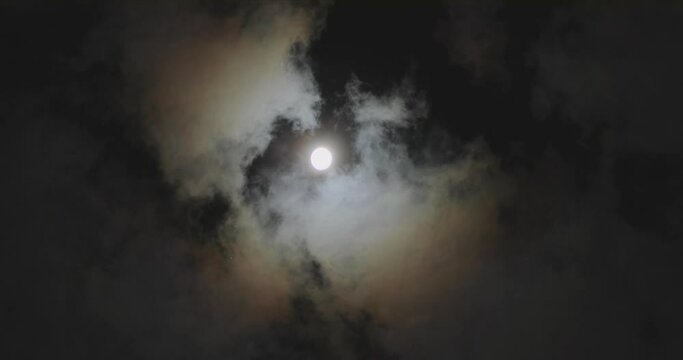 The movement of the clouds against the background of the full moon. Full moon behind clouds. Full moon.