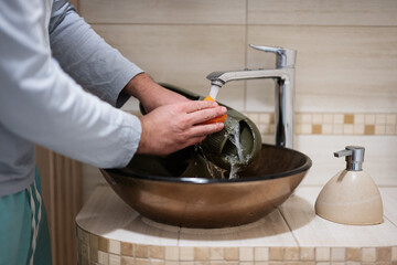 Сleaning the shoes. Man washes rubber slippers in the sink.