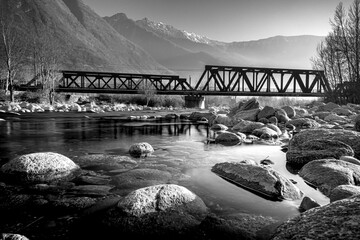 Water flowing below an old iron bridge in the Alps - 573949622
