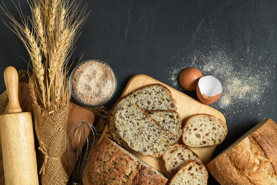 slide multi grain sourdough bread and sliced Baguette with Whole Wheat Flour on black stone background,