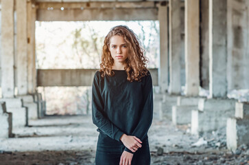 Teenage girl stands in an abandoned building. Sad, angry look of blue eyes.