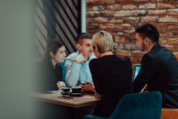Happy businesspeople smiling cheerfully during a meeting in a coffee shop. Group of successful business professionals working as a team in a multicultural workplace.