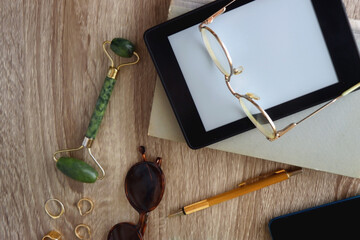 Book, tablet, phone, pen, glasses, wireless headphones, face roller, gold jewelry and leopard...