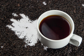 Cup of tea on a pile of loose tea leaves on a white background