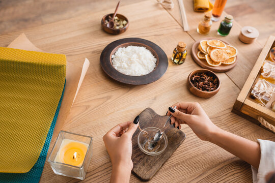 Partial View Of African American Woman Making Candle Wick Near Wax Sheets And Natural Ingredients In Craft Workshop.