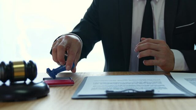 Young Asian legal advisor or lawyer doing document approval stamp Business agreements regarding real estate financial documents at the office.