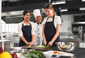 Happy student Asia woman assistant chef learning cooking of Asia senior chef and kitchen background