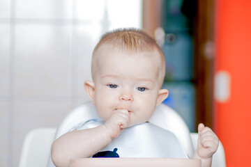 Close-up of a child's face. Grimaces of a cheery baby. Happy childhood and delicious food. Little cute kid eats with his hands. Funny child gets dirty with food