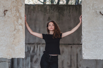 Dramatic photo of a sexy woman in an abandoned building standing among concrete structures.