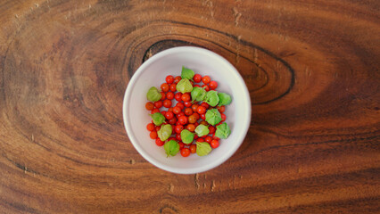 Withania somnifera or ashwagandha leaves and red fruit berries in white cup. winter cherry....