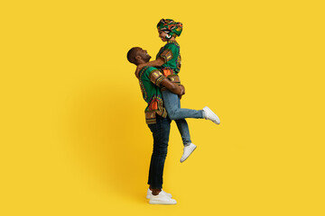 Fototapeta na wymiar Romantic black couple in african outfit cuddling on yellow