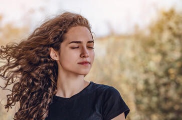 Face of a woman dreaming with closed eyes outdoors. Curly hair. Autumn.