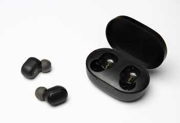 Obraz na płótnie Canvas Wireless earbuds are isolated on a white background. Headset close-up in the charging case,