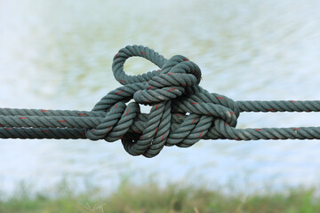 Twisted green cord on blurred water surface background. - obrazy, fototapety, plakaty