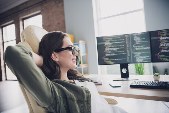 Photo of smiling positive lady hacker wear eyeglasses arms hands behind head having rest indoors workplace workstation