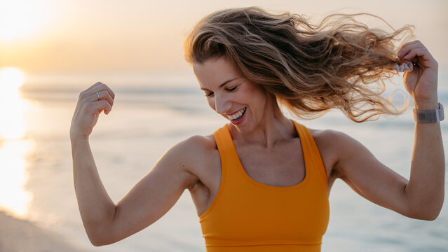 Young sportive woman showing her muscles at beach.