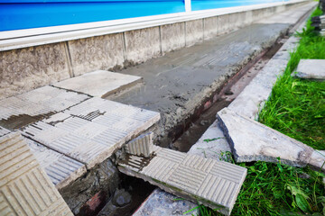 Replacement and repair of the blind area of the building. Laying stone tiles around the house. Construction theme..