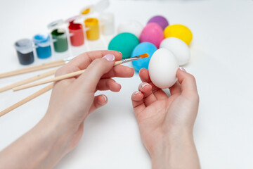 The process of painting Easter eggs. A woman is painting an Easter egg in watercolor