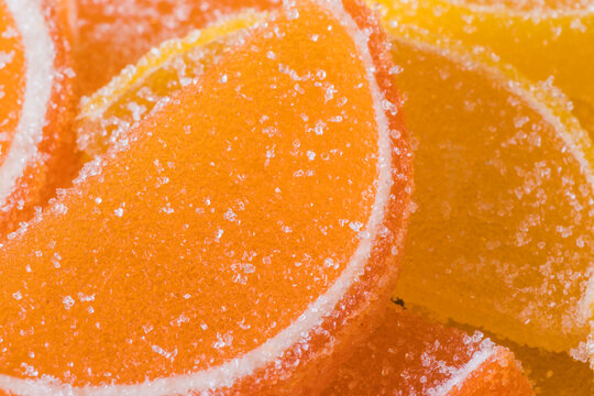 Decorative Background of yellow and orange marmalade candy in shape of citrus fruits wedges. Jelly sweet candies. Food Texture. Beautiful square Wallpaper or Web banner.