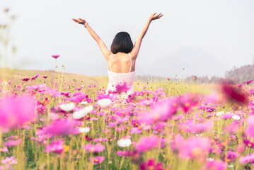 Naklejka na ściany i meble Asian woman relax and freedom in beautiful blooming cosmos flower garden. Travel happy and Lifestyle Concept.