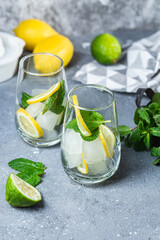 Cold lemonade with mint, lemon and lime in a glass. Preparation of lemonade