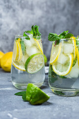 Cold lemonade with mint, lemon and lime in a glass. Preparation of lemonade