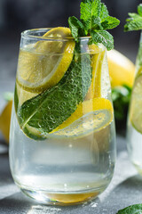 Cold lemonade with mint, lemon and lime in a glass. Preparation of lemonade