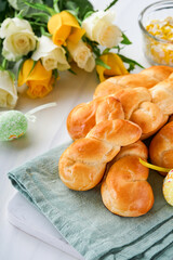 Easter breakfast Holliday concept. Easter bunny buns rolls with cinnamon made from yeast dough with orange glaze, easter decorations, colored eggs on white spring background. Easter Holliday card.