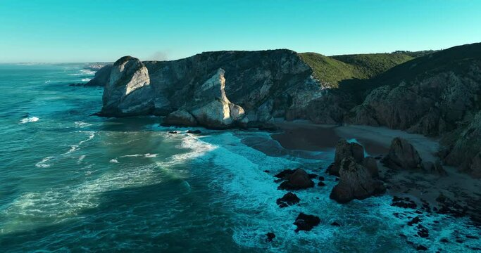 Aerial view pf the most western point of the European continent - Cabo da Roca, Portugal. Drone flies over the Atlantic ocean coast, rocky formations and the beach called Praia da Ursa.