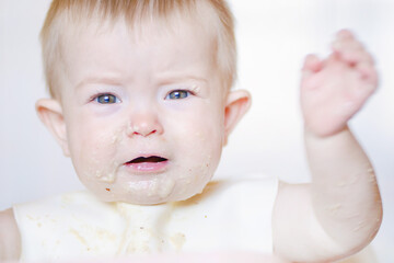 Happy childhood and delicious food. Funny child gets dirty with food. Little cute kid eats with his...