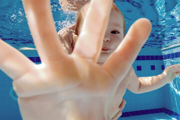 Little girl is playing in the pool. Fun with water. Cute baby swims underwater