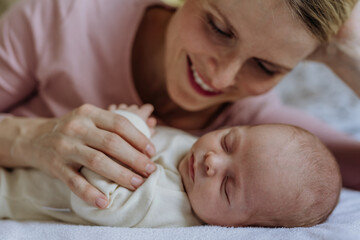 Mother cuddling with her newborn baby in their bad.