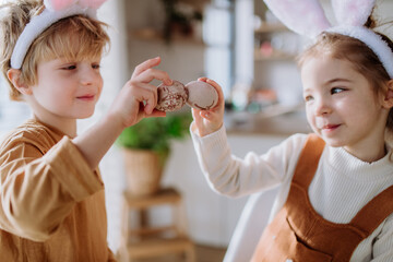 Little kids with bunny ears celebrating easter, playing easter game with egg.