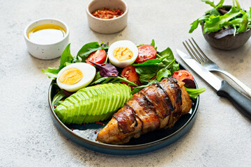 Plate with baked chicken fillet with bacon, fresh vegetables, salad.