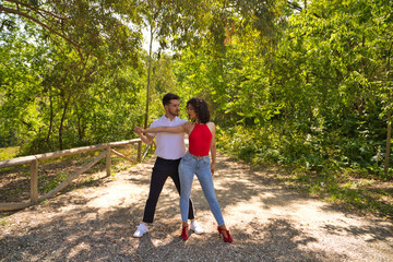 Handsome young man and woman dancing bachata and salsa in the park. The couple dance passionately...