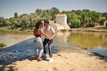 beautiful woman and handsome man latinos dancing bachata are dancing by the river in the forest....