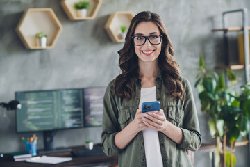 Photo of pretty positive girl executive director toothy smile hold use telephone loft interior...