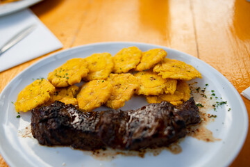 tostones with beef fillet served on white plate. Fried green plantain. Dominican food. Stepped potato.