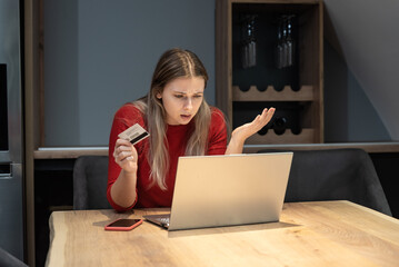 Young shocked frustrated woman holding bank credit card annoyed that she has reached her account...