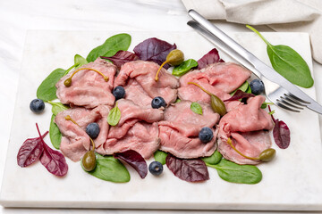 Roast beef with spinach leaves capers and blueberries