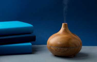wood fragrance on the desk table with natural oils essence vapor, with blue and teal colored books