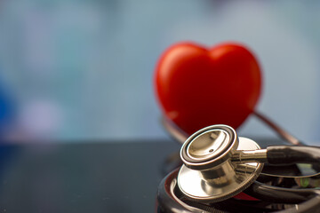 Selective focus of stethoscope on glass surface with a red heart, medical concept