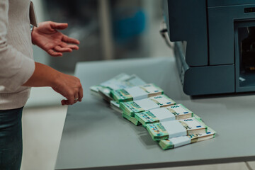 Bank employees using money counting machine while sorting and counting paper banknotes inside bank...