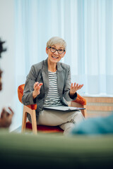 Senior woman psychiatrist talking with her patients during therapy session