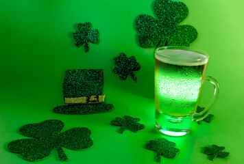Beer mug with green light on green background with shamrock and hat, st patrick's day